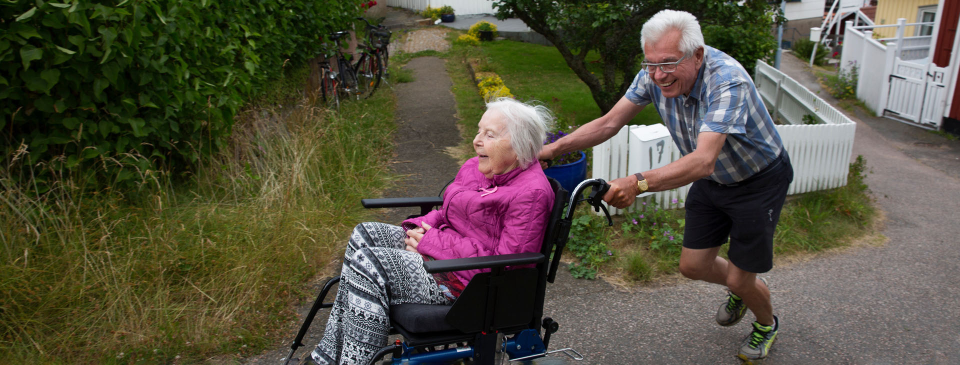 Man och kvinna som är ute på promenad. Kvinnan sitter i rullstol.
