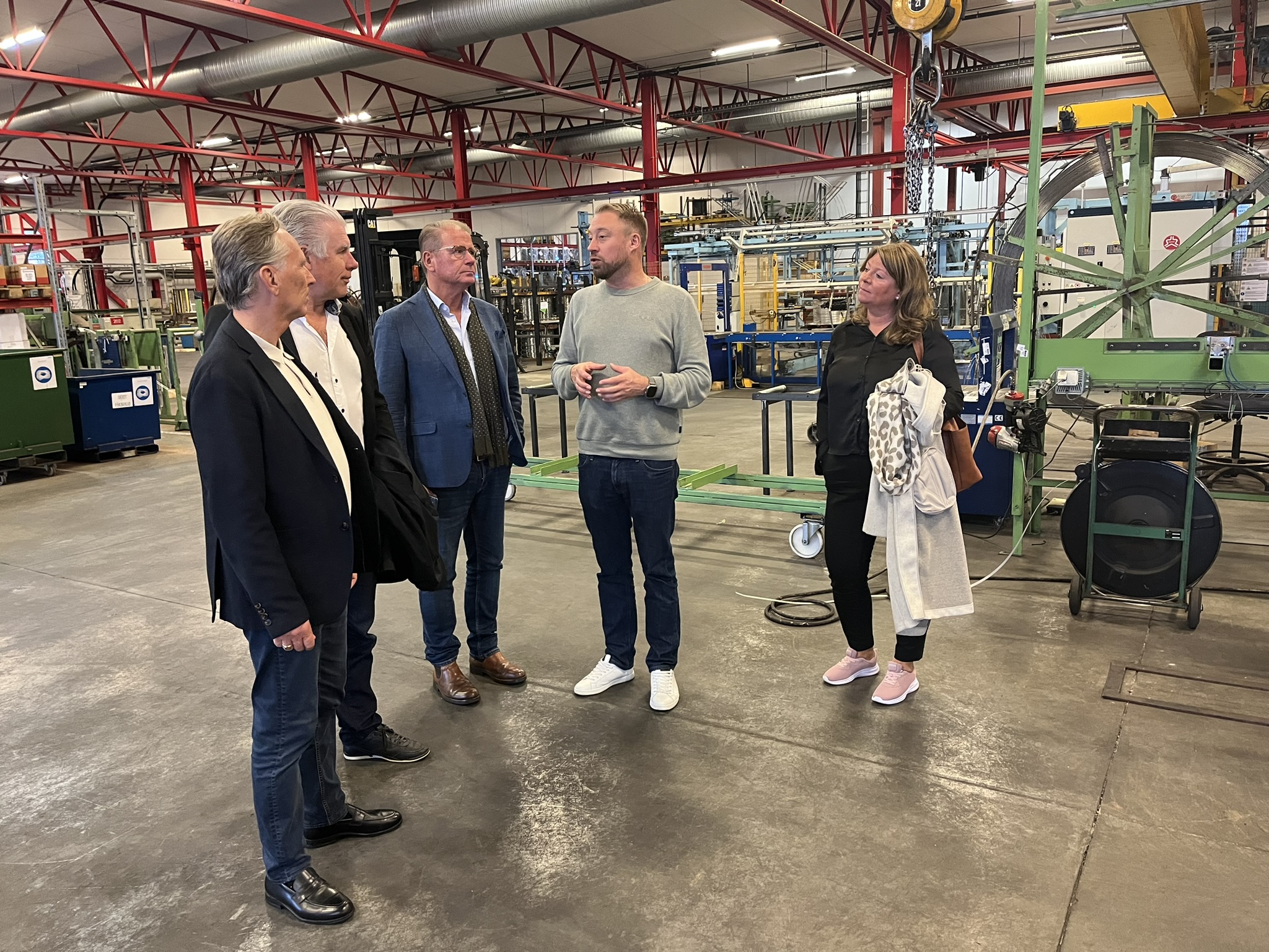 En grupp människor i fabrikslokal. 