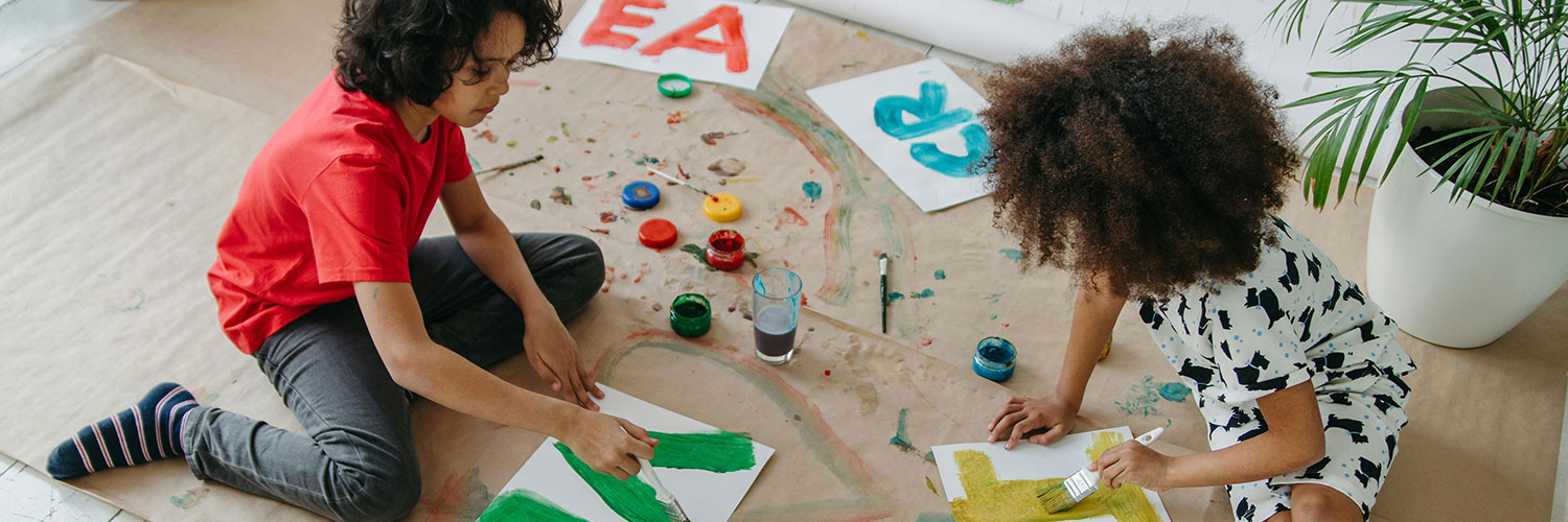 Barn som sitter på golvet och målar teckningar