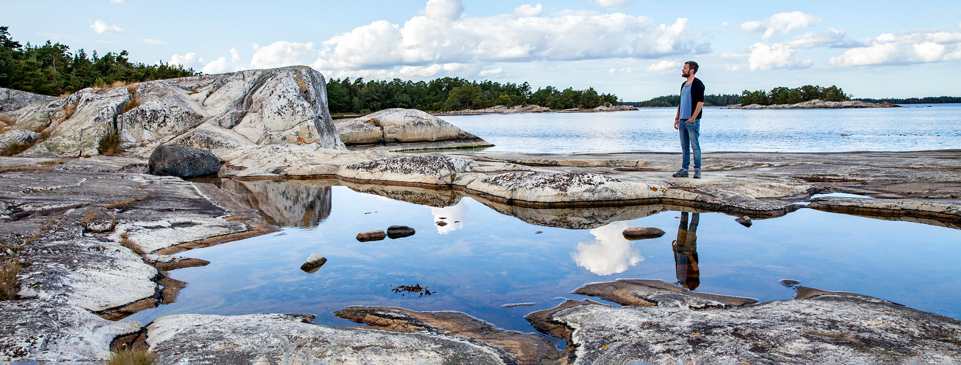 Man som står på klippa vid havet. 