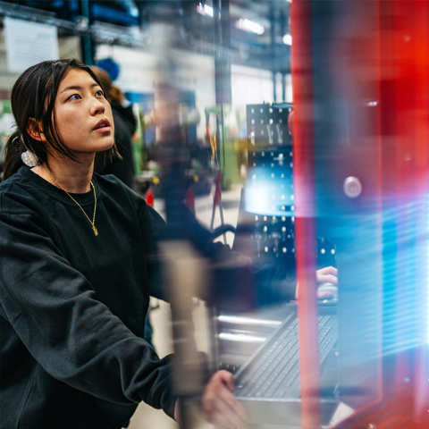 Bild på en kvinna som står vid en maskin och arbetar.