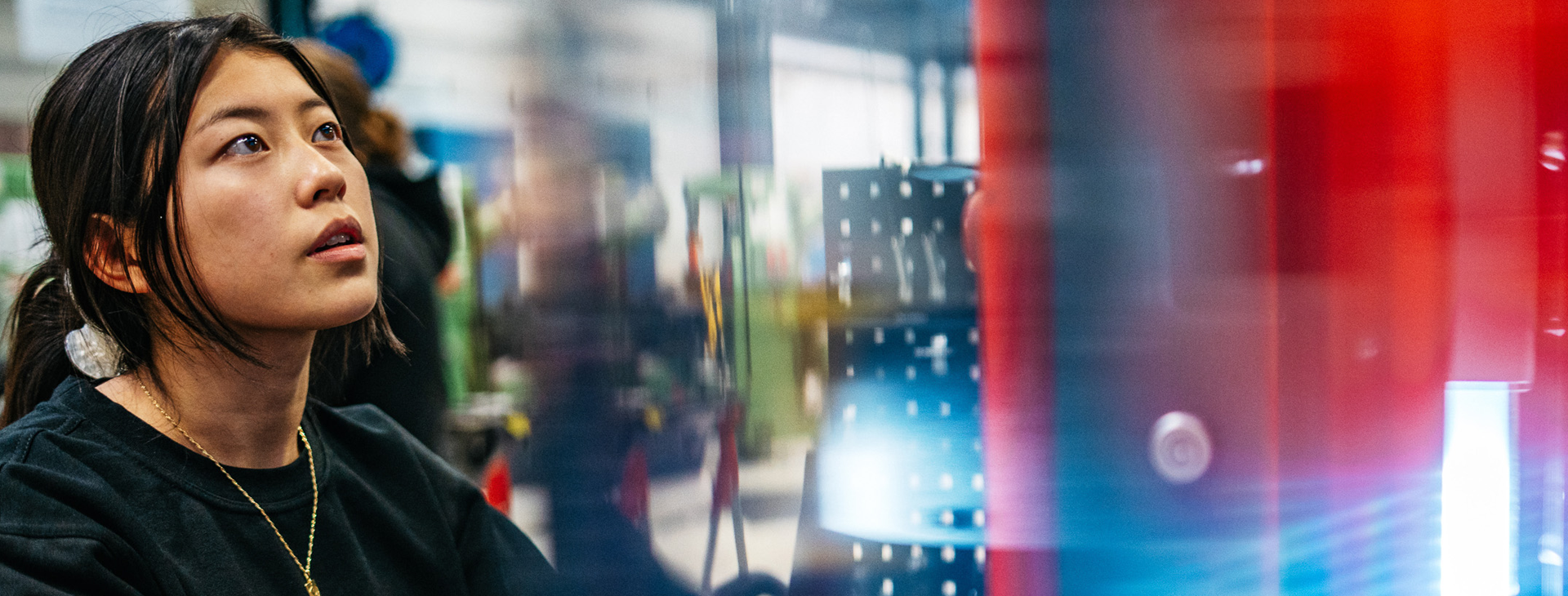 Bild på en kvinna som står vid en maskin och arbetar.