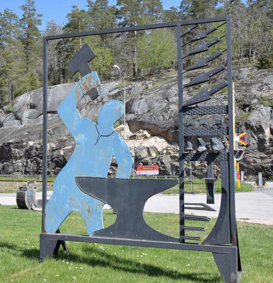 Verket föreställer en smed som slår på sitt städ. 