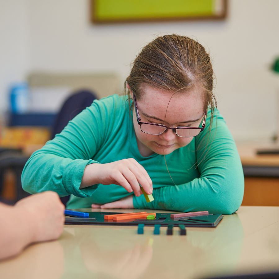 Flicka med down syndrom som bygger med klossar efter mönster.