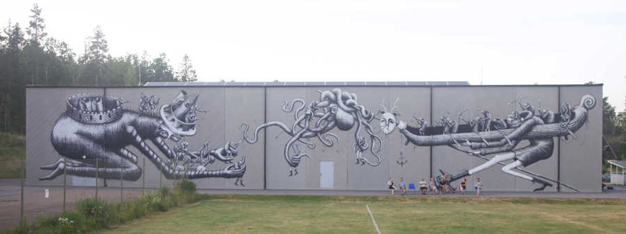 Väggmålning föreställande två långa fantasifigurer som böjer sig fram och håller i människofigurer.