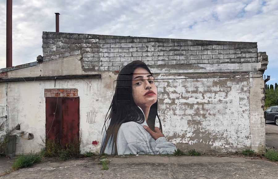 Väggmålning föreställande en ung kvinna med långt mörkt hår. 