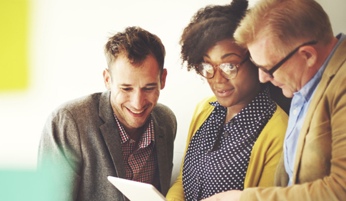 Tre personer som tillsammans tittar på ett informationsblad.