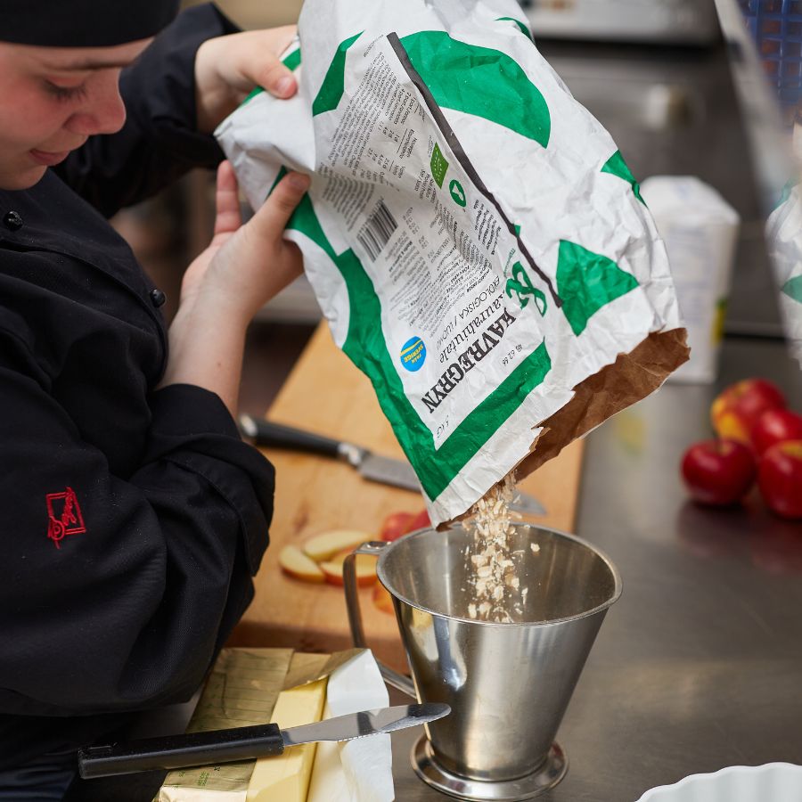 Tje med kockmössa som häller ut mjöl.