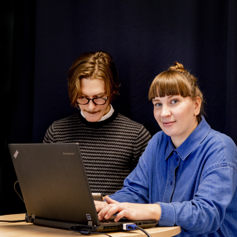 Två studerande som står vid en dator.