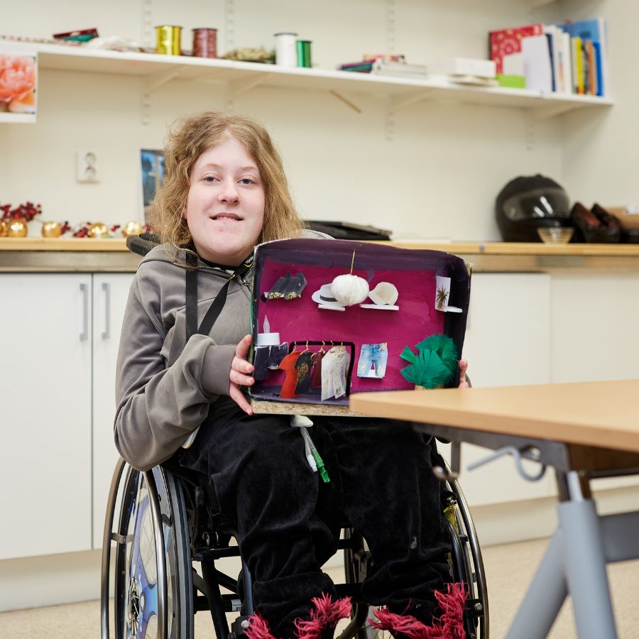 Tjej i rullstol som visar upp något hon byggt.