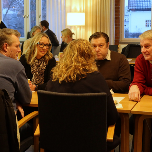 Fyra personer pratar och ler vid ett bord 