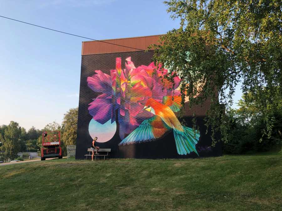 Väggmålning föreställande flygande fågel som suger nektar ur blomma.