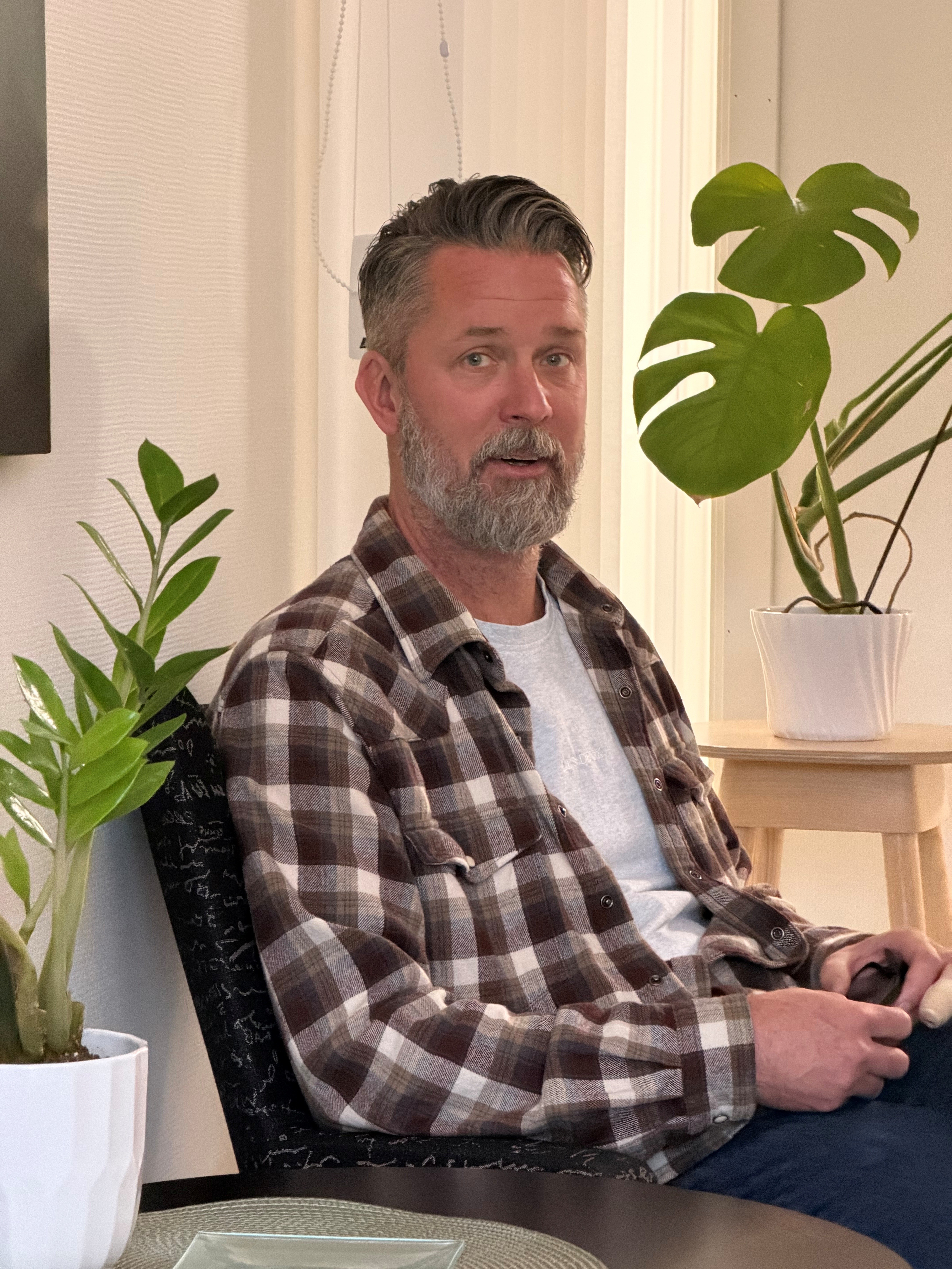 En man i en fåtölj med blommor omkring.