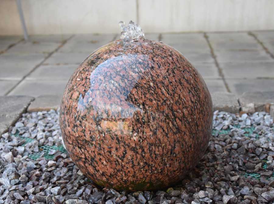 Ett polerat stenklot som det rinner vatten ifrån.