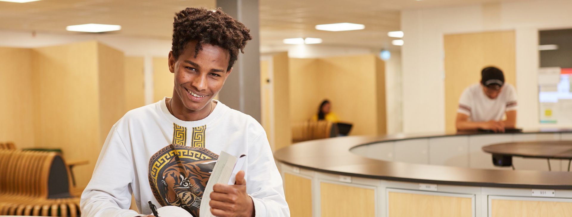 Pojke som bläddrar i en bok och ler. 