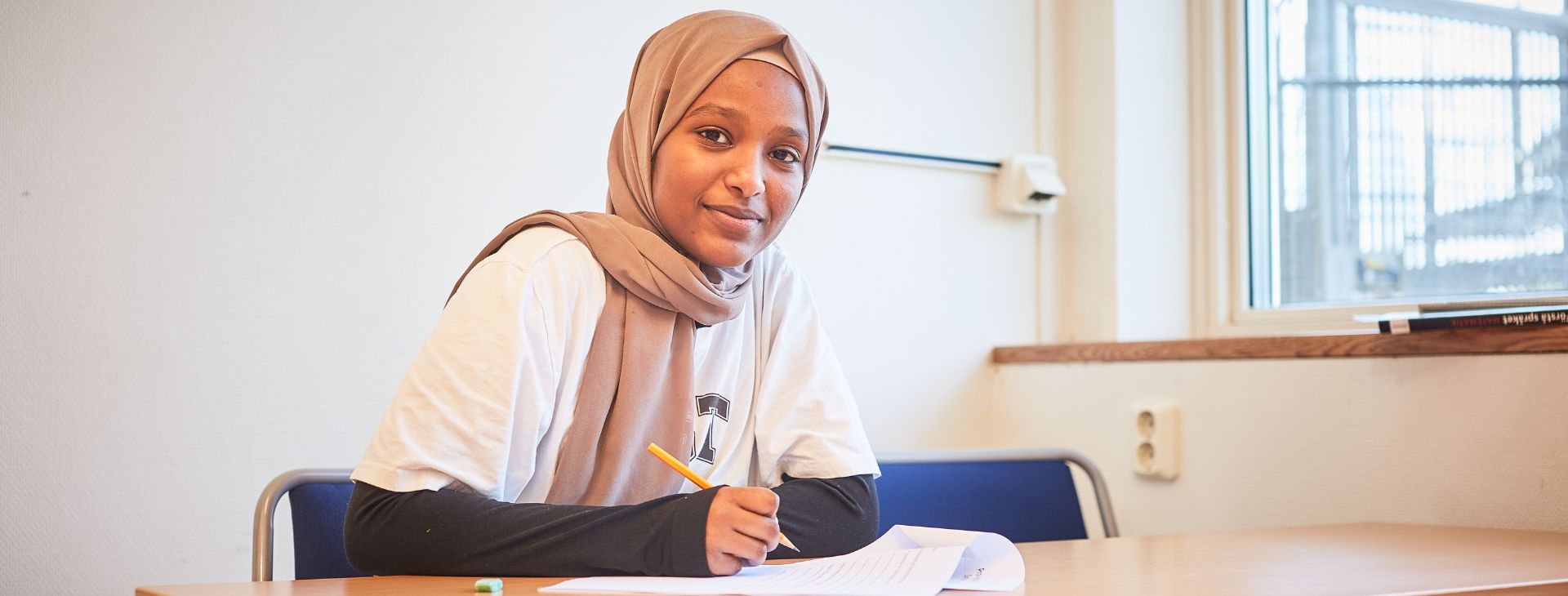 Flicka som bläddrar i en bok och ler. 