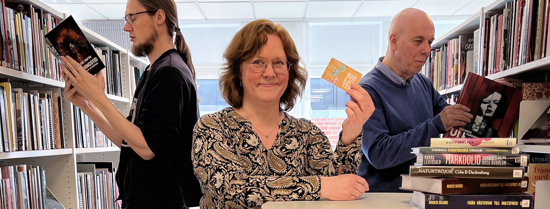 Bibliotekarier som står bland bokhyllor. 