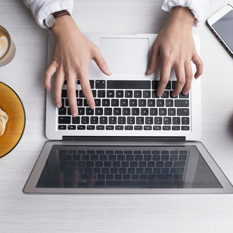 Bild på två händer som skriver på en laptop.