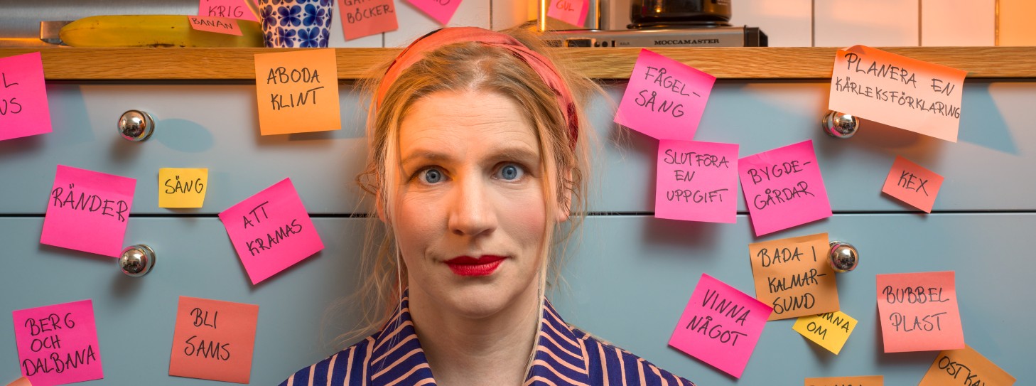 En kvinna framför en vägg med många postitlappar. 