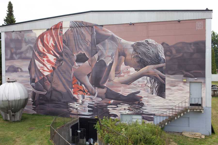 Väggmålning föreställande en kvinna som tvättar sitt hår i en flod.