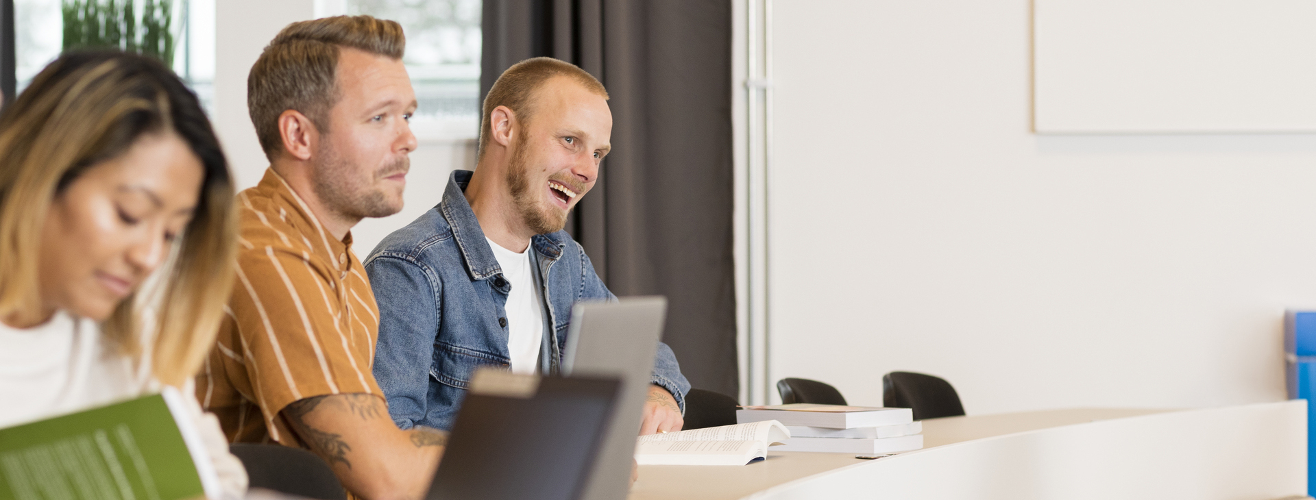 Tre glada studenter som är på föreläsning.