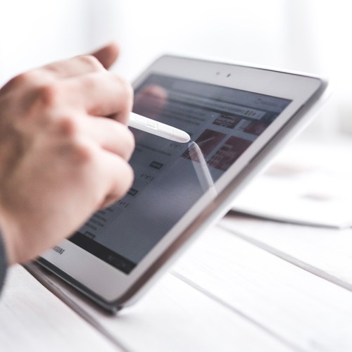 Bild visar en persons hand som jobbar med surfplatta.