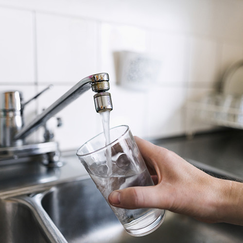 bild på glas som fylls på med vatten ur en kökskran