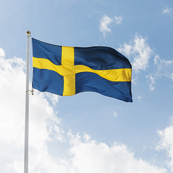Svensk flagga mot blå himmel med vita moln. 