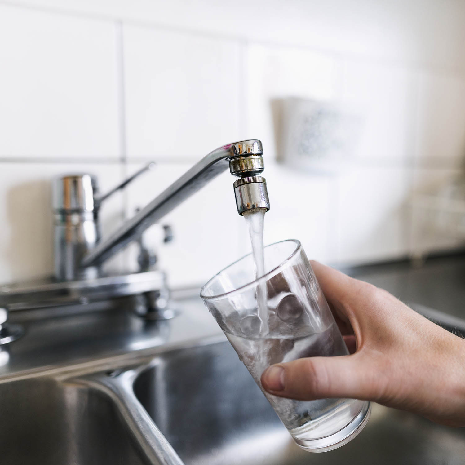 bild på vattenkran med hand som håller glas