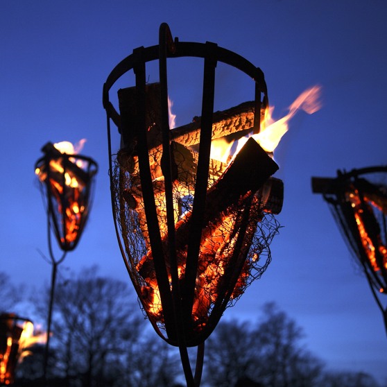 Brinnande eldkorg i skymning.