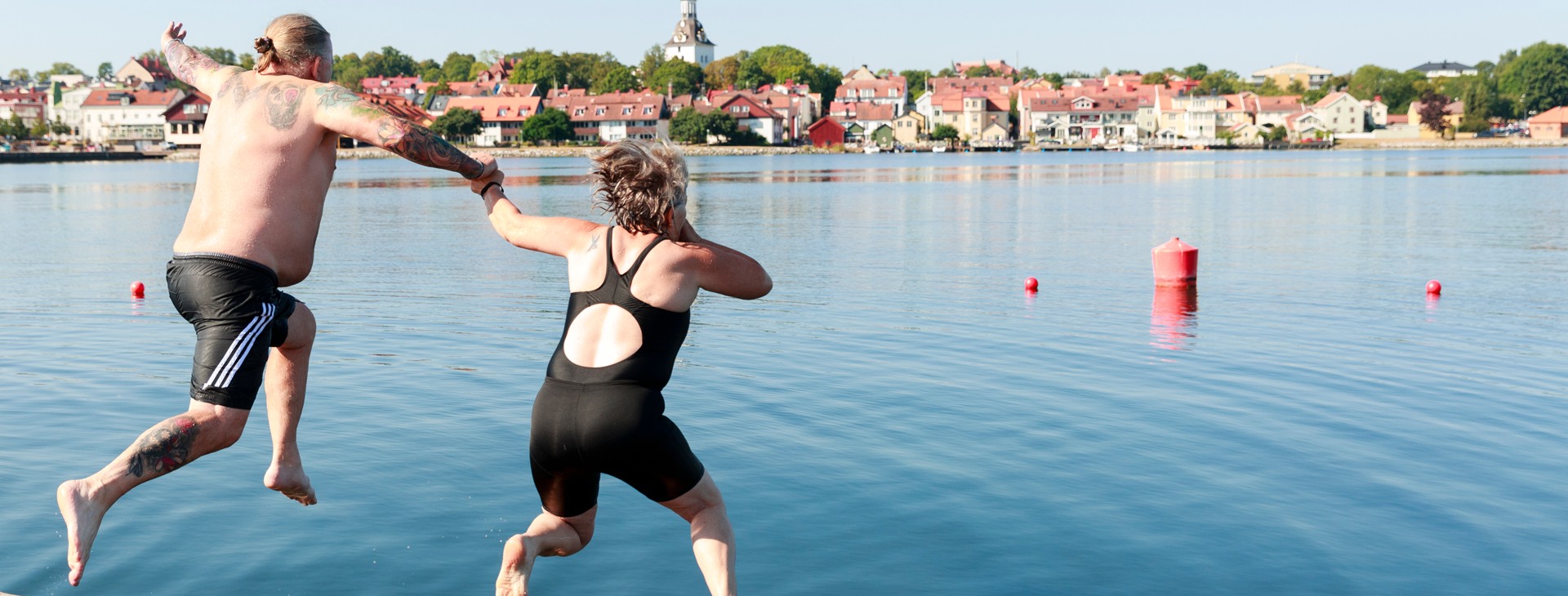 Man och kvinna som hoppar i vattnet.