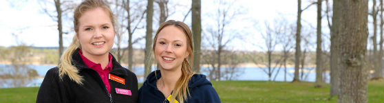 Fanny och Martina med träd och havsvik i bakgrunden